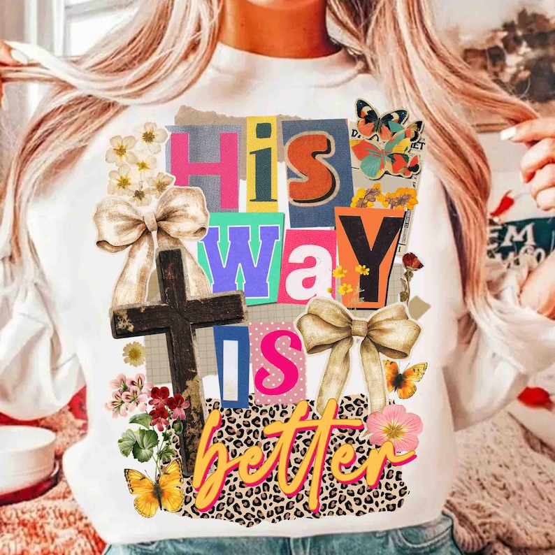 May include: White sweatshirt with the text "His Way Is Better" in colorful block letters. The design includes a wooden cross, bows, flowers, butterflies, and a leopard print pattern.