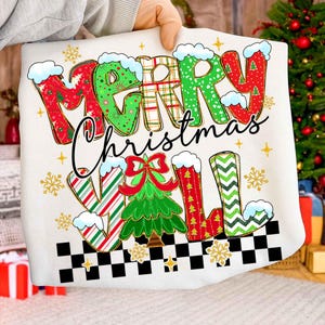 May include: A white Christmas-themed graphic featuring the text "MERRY CHRISTMAS Y'ALL" in festive colors and patterns. The design includes snowflakes, a Christmas tree, and a checkered border, perfect for holiday apparel or decor.