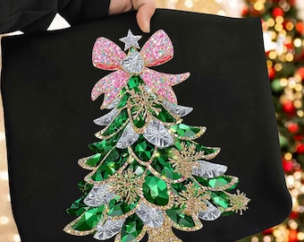 May include: Black Christmas-themed pillow featuring a sparkling Christmas tree design. The tree is adorned with green and silver gems, gold accents, and a pink glitter bow. A star tops the tree.