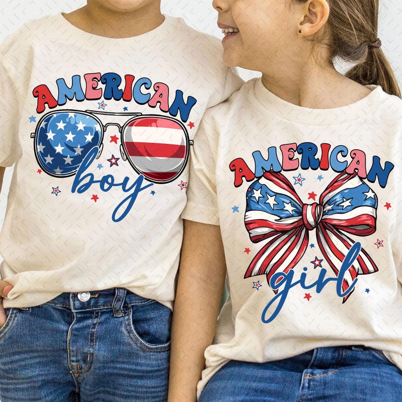 May include: Two cream-colored t-shirts with patriotic designs. One shirt features sunglasses with a star-spangled lens and a red and white striped lens, with the words "American boy." The other shirt has a bow with red, white, and blue stripes and stars, with the words "American girl."