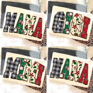May include: Four decorative pillows with names: "MAMA", "GIGI", "MIMI", and "NANA". Each name is in large, block letters. The letters are a mix of black and grey plaid, green with Christmas designs, and red with Christmas tree patterns. The pillows are on a cream-coloured surface.