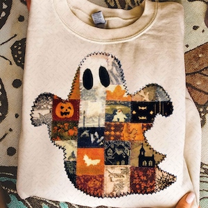 Puede incluir: Sudadera beige con un diseño de fantasma de patchwork. El fantasma está hecho de cuadrados de tela con imágenes de Halloween como calabazas y murciélagos. El fantasma tiene ojos ovalados negros y un contorno cosido en zigzag.