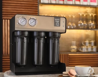 May include: A stainless steel water filtration system with four filter cartridges. The system has a digital display and two pressure gauges. The system is sitting on a marble countertop next to a cup of coffee and two macarons.