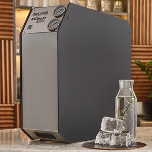 Puede incluir: Un sistema de filtración de agua con el texto "Decosoft Robust 4000" en la parte delantera. El sistema tiene una parte delantera de acero inoxidable y un panel lateral gris oscuro. Una botella de vidrio con agua y cubitos de hielo está frente al sistema.