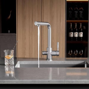 May include: A chrome kitchen faucet with a single lever handle and a spout that extends out over a stainless steel sink. Water is flowing from the spout into the sink.