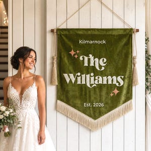 Puede incluir: Un estandarte de pared rectangular de terciopelo verde oliva con el texto "Kilmarnock", "The Williams" y "Est. 2026" en letras blancas. El estandarte está decorado con cuatro pequeñas estrellas de color cobre y cuelga de una vara de madera con borlas.