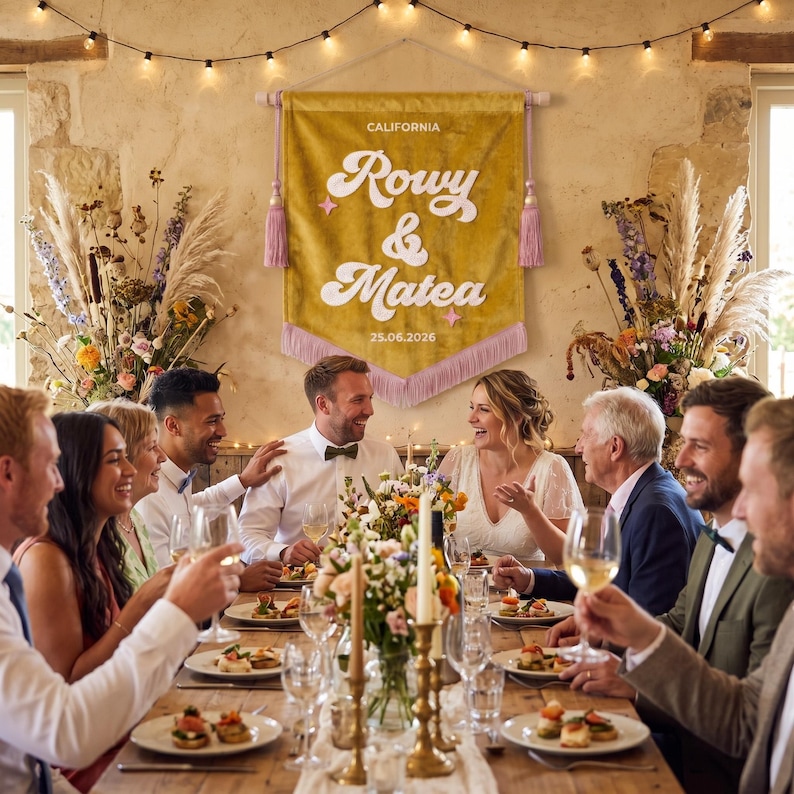May include: A mustard yellow fabric wall banner featuring the text CALIFORNIA, Rowy & Matea, and 05.26.2026 in white lettering. The banner has a pointed bottom edge with light purple fringe and is suspended by a wooden rod with purple tassels.
