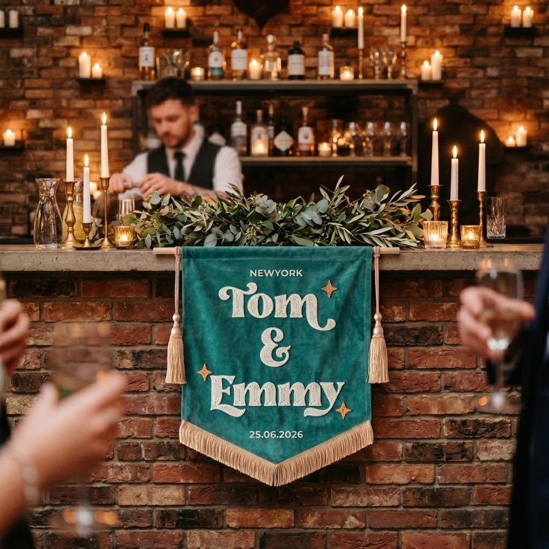May include: A teal velvet wall banner featuring the white embroidered text NEWYORK, Tom & Emmy, and 25.06.2026. The banner is accented with gold star motifs, hanging from a wooden rod with beige tassels on each side and a matching fringe at the bottom.