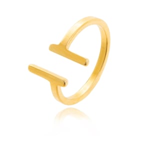May include: A gold-colored ring with a modern, open design. The ring features two parallel, rectangular bars that extend from the band, creating a unique and contemporary look. The ring is set against a white background.