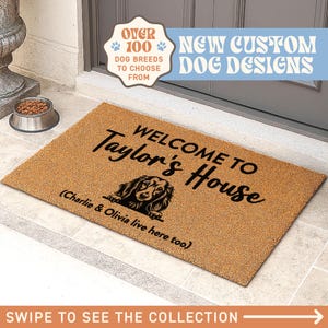 Op de afbeelding: Een rechthoekige deurmat met de tekst "WELCOME TO Taylor's House" en een hondenillustratie. De tekst "(Charlie & Olivia live here too)" staat eronder. De mat is bruin met zwarte tekst.