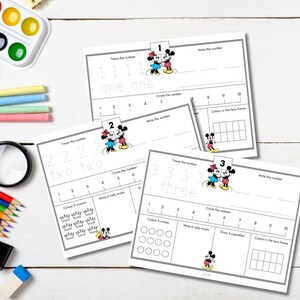 May include: Educational worksheets for learning numbers 1, 2, and 3. Each worksheet features tracing, writing, and counting exercises, with illustrations of Mickey and Minnie Mouse. Includes a magnifying glass, crayons, and watercolor paints.