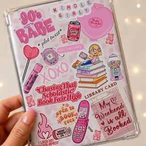 Może przedstawiać: Przezroczyste etui ochronne na tablet z kolażem różowych naklejek, zawierające napisy takie jak 90's BABE, Chasing That Scholastic Book Fair High oraz My Weekend is all Booked, wraz z ilustracjami telefonu z klapką, książek i słodyczy.