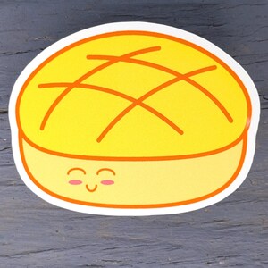 May include: A yellow sticker featuring a cartoon illustration of a smiling pineapple bun. The bun has a yellow top with orange crosshatch lines and a light yellow base. The sticker has a white border.
