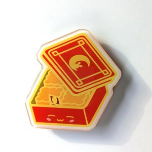 May include: A red and yellow cartoon box with a lid open, revealing a yellow and orange filling. The box has a cute face with closed eyes and a smile.