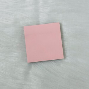 May include: A pink sticky note on a white fuzzy surface.