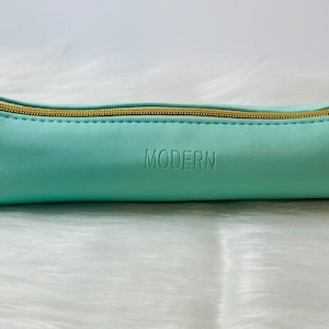 May include: A light blue pencil case with a gold zipper and the word "MODERN" embossed on the front.