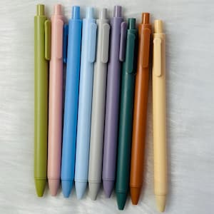 Peut inclure: Un ensemble de dix stylos de couleurs sourdes, y compris le vert, le rose, le bleu, le gris, le violet, le marron et le beige. Les stylos sont disposés en rangée, les pointes face au spectateur.