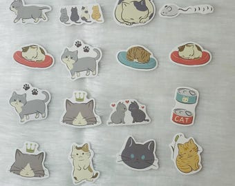 May include: A collection of cat-themed stickers in various poses and colors. The stickers feature cats sleeping, playing, and with crowns. Some stickers include paw prints and cat food cans. The stickers are on a white, fluffy surface.