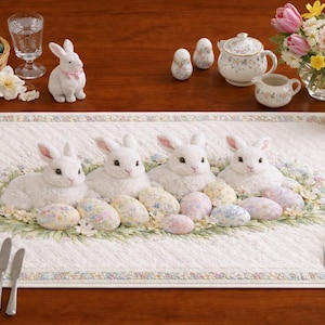 Könnte beinhalten: Oster-Tischdekoration mit einem weißen, gesteppten Tischläufer mit vier weißen Hasenfiguren und pastellfarbenen Eiern. Zusätzliche Dekorationen umfassen einen Eierkorb, ein Blumenarrangement und dekorative Porzellanstücke.