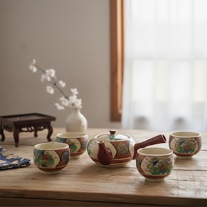May include: A Japanese tea set with a teapot and four matching cups, all decorated with colorful floral and geometric patterns. The teapot has a side handle and a lid. The cups and teapot are arranged on a wooden table.