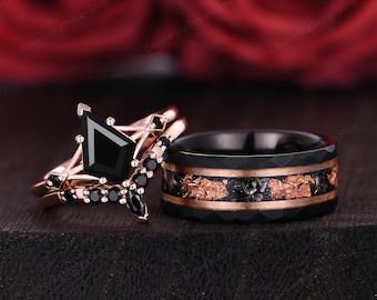 May include: A rose gold and black engagement ring set. The engagement ring features a black diamond and black accents. The matching band is black with gold and black accents. The rings are displayed on a dark surface.