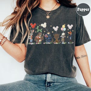 Puede incluir: Camiseta gris oscuro con un gr&aacute;fico de dibujos animados de animales sosteniendo globos. El dise&ntilde;o incluye un conejo, un perezoso, un oso, un tigre, una oveja y un zorro. La palabra "Pepper" est&aacute; en un c&iacute;rculo en la parte superior derecha.