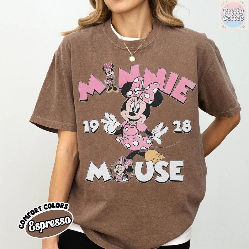 Puede incluir: Camiseta color espresso con un dise&ntilde;o de Minnie Mouse. El dise&ntilde;o incluye las palabras "MINNIE MOUSE" en rosa, junto con los n&uacute;meros "1928". La camiseta tiene un aspecto vintage, ligeramente descolorido.