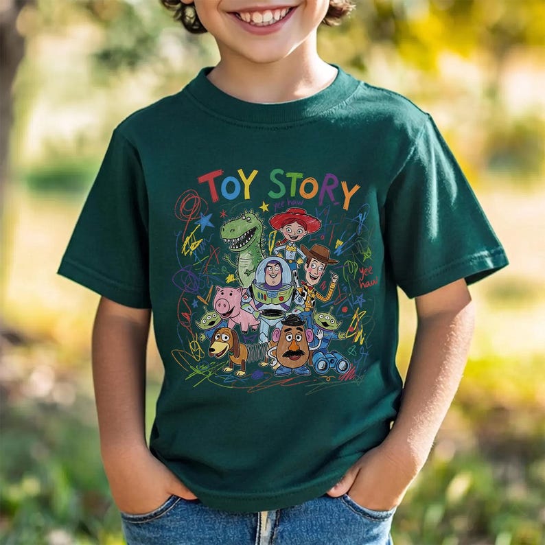 May include: A dark green t-shirt featuring the words "TOY STORY" in colorful letters above a graphic of characters from the animated film. The design includes Woody, Buzz Lightyear, Rex, and other characters.