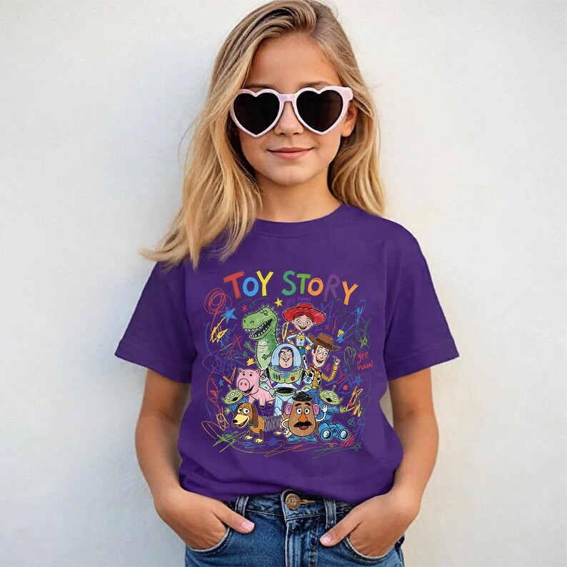 May include: A purple t-shirt featuring the words "TOY STORY" in colorful letters above a graphic of characters from the animated movie. The shirt is worn by a person wearing heart-shaped sunglasses.