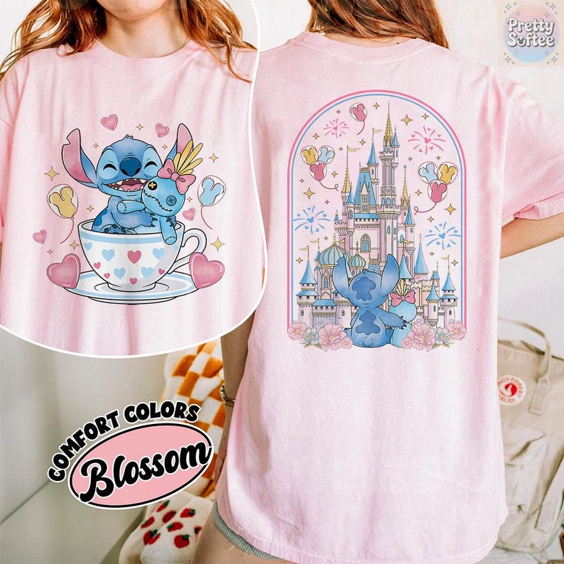 May include: Pink t-shirt featuring a cartoon Stitch character with a teacup design on the front and a castle scene on the back. The front design shows Stitch in a teacup with hearts. The back design shows Stitch in front of a castle.