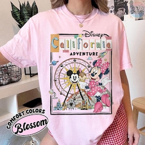 Puede incluir: Camiseta rosa claro Comfort Colors con un gr&aacute;fico de Mickey y Minnie Mouse frente a una noria, con el texto "California Adventure". La camiseta tambi&eacute;n tiene el texto "Comfort Colors Blossom".