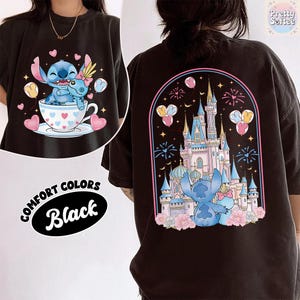 May include: Black Comfort Colors t-shirt featuring a cartoon illustration of Stitch in a teacup with hearts and balloons. The back of the shirt displays a castle scene with Stitch, fireworks, and balloons. The text "Comfort Colors Black" is also visible.