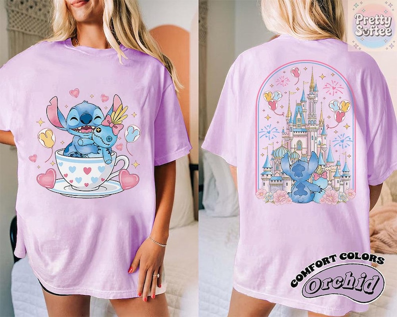 May include: A light purple t-shirt featuring a cartoon Stitch character in a teacup with hearts and balloons. The back of the shirt shows Stitch in front of a castle with fireworks. The shirt has the words "Pretty Softee" and "Comfort Colors Orchid".