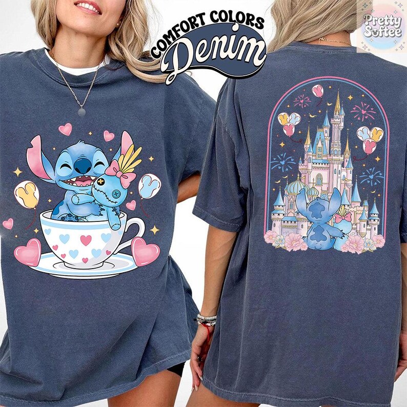 May include: Denim blue t-shirt featuring a cartoon character in a teacup with hearts and the text "Comfort Colors Denim". The back of the shirt shows a castle scene with the same character. The shirt has short sleeves.