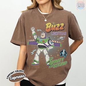 May include: Espresso-coloured t-shirt with a Buzz Lightyear graphic from Toy Story. The design includes the text "Buzz Lightyear" and "To Infinity and Beyond." The shirt has a crew neck and short sleeves.