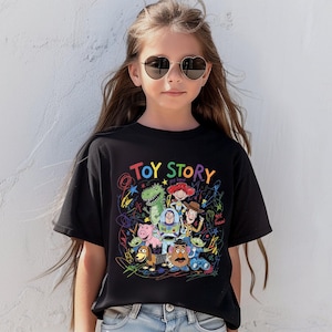 May include: Black t-shirt featuring a colorful graphic of Toy Story characters and the words "Toy Story" in rainbow letters. The design includes Woody, Buzz Lightyear, and other characters from the animated film.