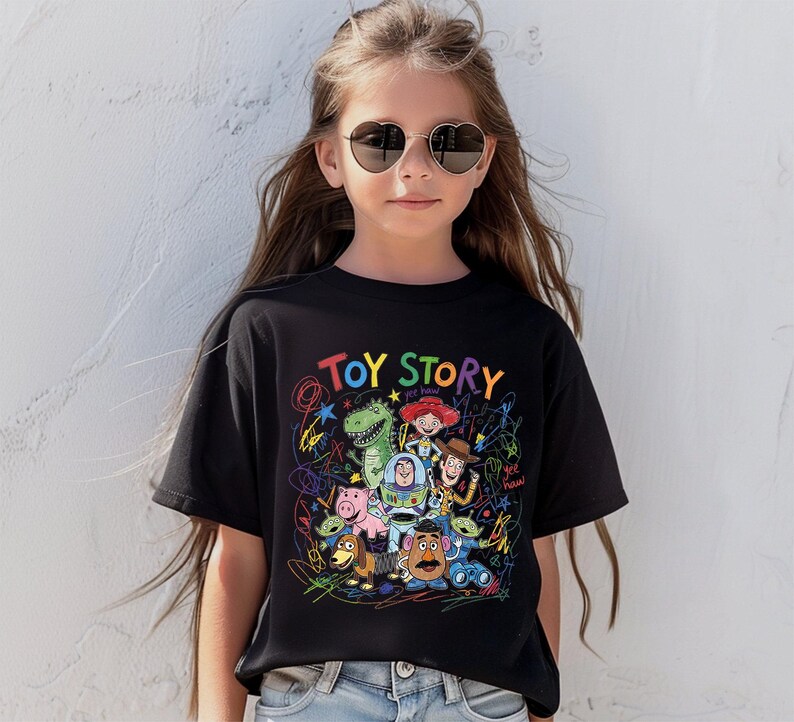 May include: Black t-shirt featuring a colorful graphic of Toy Story characters and the words "Toy Story" in rainbow letters. The design includes Woody, Buzz Lightyear, and other characters from the animated film.