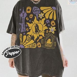 K&ouml;nnte beinhalten: Dunkelgraues &uuml;bergro&szlig;es T-Shirt mit einem Grafikdesign mit Sonne, Blumen und Text. Der Text enth&auml;lt "Best Day Ever", "I See The Light" und "The Snuggly Duckling". Das Shirt hat auch die W&ouml;rter "Comfort Colors" und "Pepper".