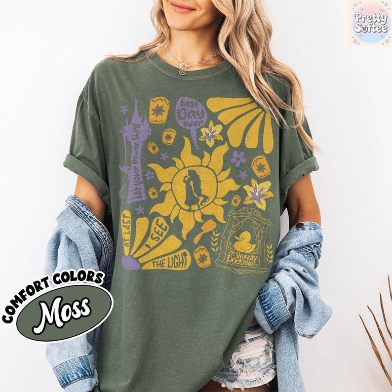 K&ouml;nnte beinhalten: Moosgr&uuml;nes T-Shirt mit einem grafischen Design mit einer Sonne, einer Personensilhouette und dem Text &bdquo;Best Day Ever&ldquo; und &bdquo;I See The Light&ldquo;. Das Shirt tr&auml;gt auch die Aufschrift &bdquo;Comfort Colors&ldquo; und &bdquo;Moss&ldquo;.