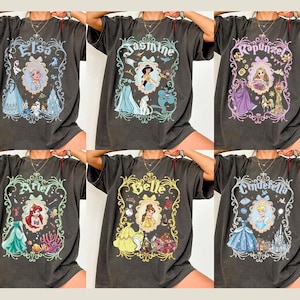 Pu&ograve; includere: T-shirt grigio scuro con disegni di principesse Disney. Ogni maglietta presenta una principessa diversa: Elsa, Jasmine, Rapunzel, Ariel, Belle e Cenerentola. I disegni includono ritratti e illustrazioni a tema.