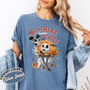 May include: Blue jean-colored t-shirt with a graphic featuring Jack Skellington from The Nightmare Before Christmas. The design includes pumpkins, bats, and the text "Nightmare on Main Street."