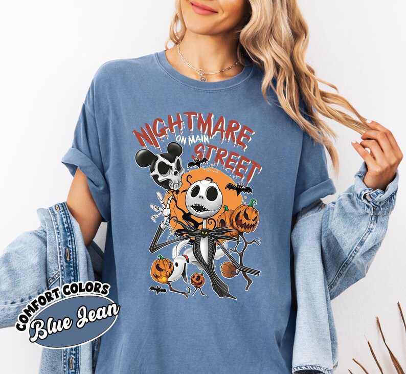 May include: Blue jean-colored t-shirt with a graphic featuring Jack Skellington from The Nightmare Before Christmas. The design includes pumpkins, bats, and the text "Nightmare on Main Street."