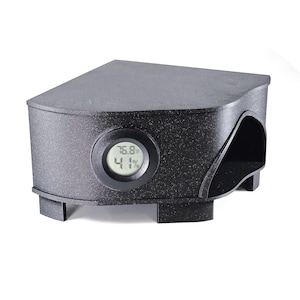 May include: Black corner-shaped device with a digital display showing 76.8 degrees and 41%. The device has a textured surface and a curved opening on the side. It appears to be a temperature and humidity sensor.