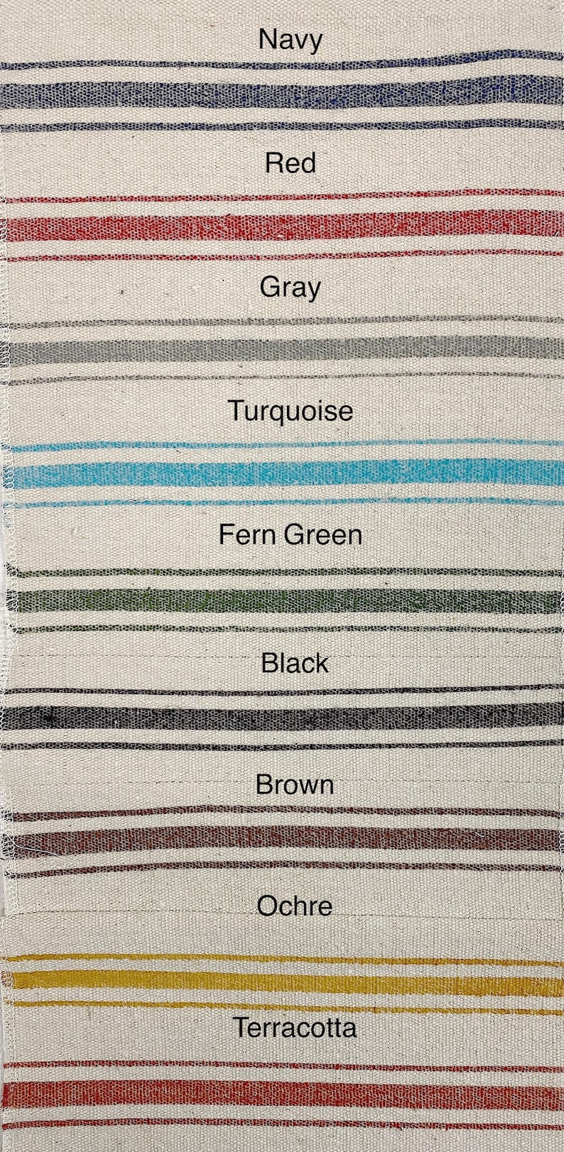 May include: A close-up of a fabric swatch with different colored stripes. The colors are navy, red, gray, turquoise, fern green, black, brown, ochre, and terracotta.