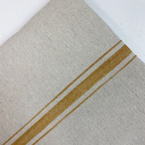May include: A piece of off-white linen fabric with two wide, horizontal, mustard yellow stripes.