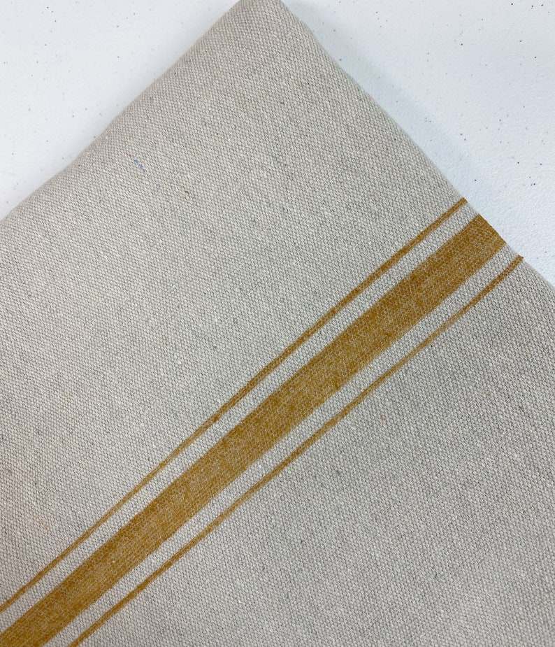 May include: A piece of off-white linen fabric with two wide, horizontal, mustard yellow stripes.