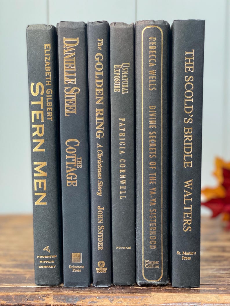 May include: A collection of six hardcover books with dark gray covers and gold lettering. Titles include "Stern Men," "Cottage," and "The Golden Ring." The books are arranged vertically, showcasing their spines. The books are from various publishers.