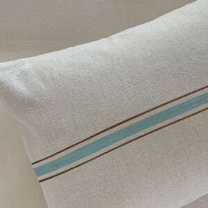 May include: A white pillow with a brown and light blue stripe pattern.