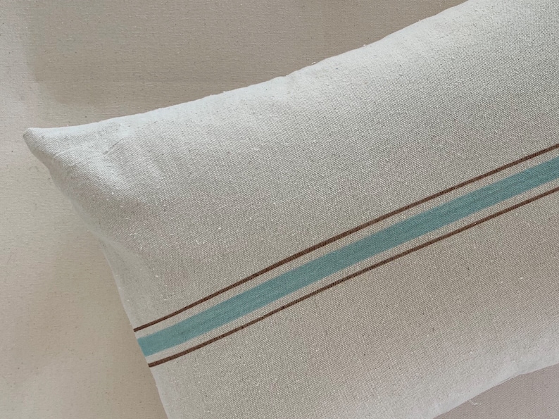 May include: A white pillow with a brown and light blue stripe pattern.