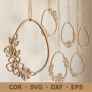 May include: Wooden oval-shaped ornaments with floral and leaf cutouts, suspended by twine. The ornaments vary in design, with some featuring full floral arrangements and others with partial leaf patterns. The bottom of the image displays the text: CDR • SVG • DXF • EPS.